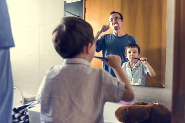 Padre enseñando a hijo a cepillarse los dientes — Foto de Stock