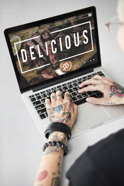 Dövmeli kişi dizüstü bilgisayarda yazarak