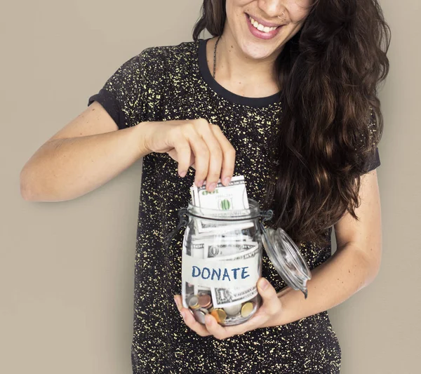 Woman putting money in jar — Stock Photo, Image