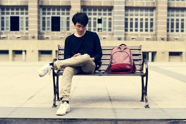Diák ül a padon, és a gazdaság notebook — Stock Fotó