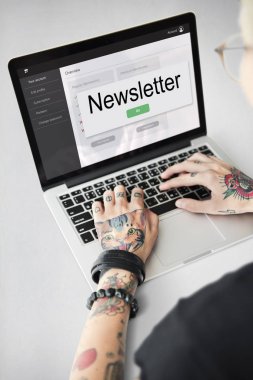 Dövmeli kişi dizüstü bilgisayarda yazarak.