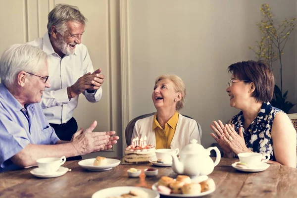 Femme âgée avec des amis et gâteau d'anniversaire — Photo