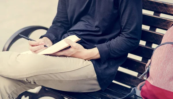 Student sedí na lavičce a drží notebook — Stock fotografie