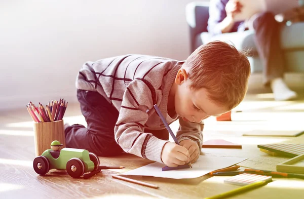 Маленький мальчик рисует на бумаге альбома — стоковое фото