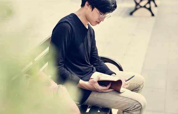 Student sedí na lavičce a drží notebook — Stock fotografie