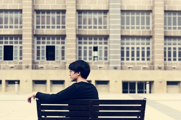 Uomo seduto sulla panchina di fronte all'edificio — Foto Stock