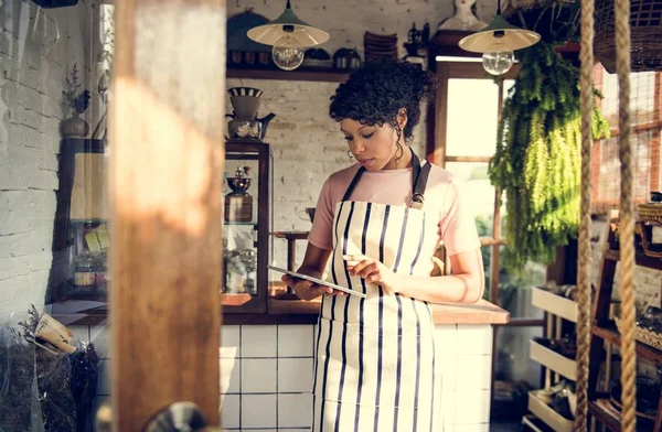 Afrikaanse vrouw in schort werken in shop — Stockfoto