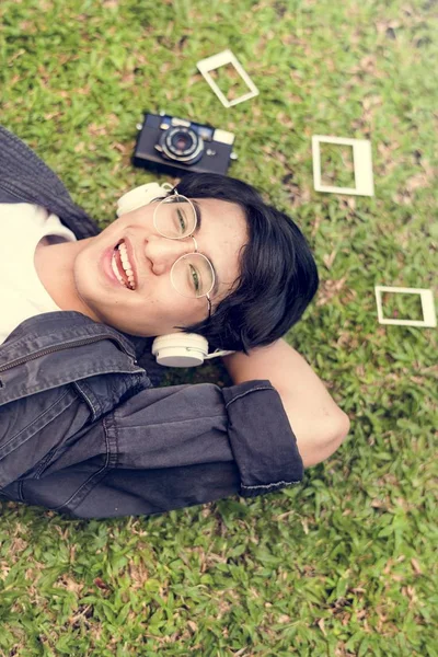 Asiático chico acostado en hierba en auriculares —  Fotos de Stock