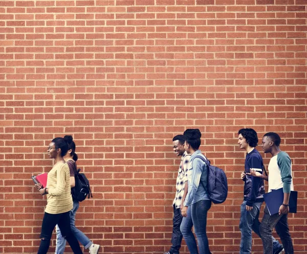 Étudiants marchant au mur de briques — Photo