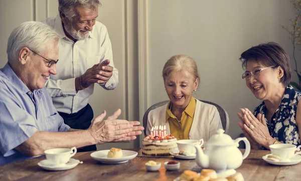 Mulher sênior com amigos e bolo de aniversário — Fotografia de Stock