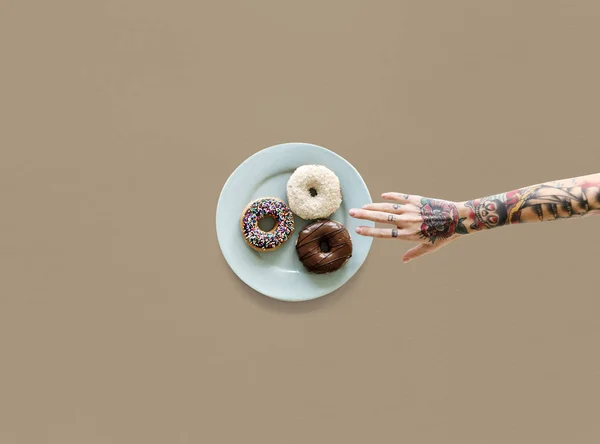 Руки и пончики на тарелке — стоковое фото