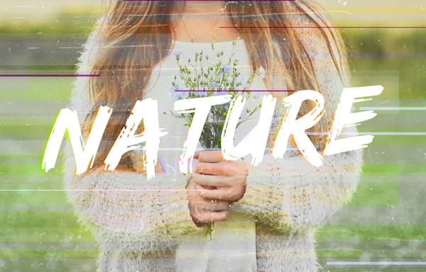 Woman standing in field and holding flowers — Stock Photo, Image