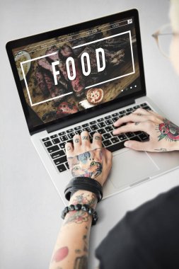 Dövmeli kişi dizüstü bilgisayarda yazarak