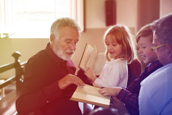 Priest Showing Bible to Kids