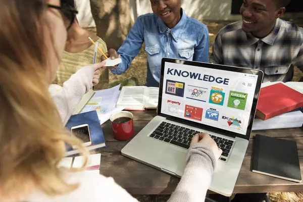 Studenti seduti a tavola con libri e laptop — Foto Stock