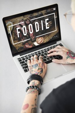 Dövmeli kişi dizüstü bilgisayarda yazarak