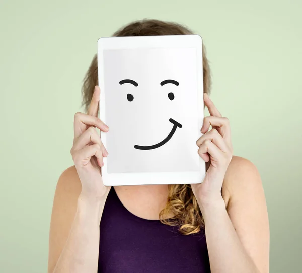 Kobieta trzyma cyfrowego tabletu obejmujący twarz — Zdjęcie stockowe