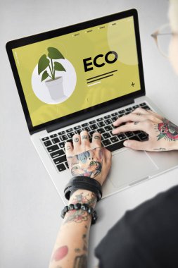 Dövmeli kişi dizüstü bilgisayarda yazarak.