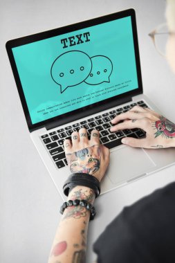 Dövmeli kişi dizüstü bilgisayarda yazarak.