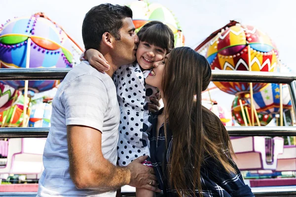 Happy parents kissing daughter