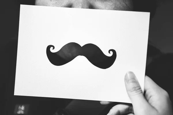 Hand Holds Card Carving Symbol Mustache Person Face Background — Stock Photo, Image