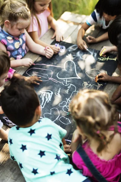 Barn rita med kritor på den svarta linjen — Stockfoto
