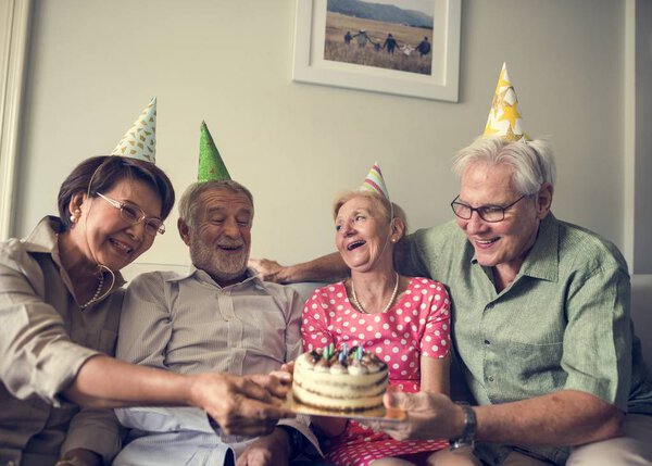 пожилые люди держат торт день рождения
