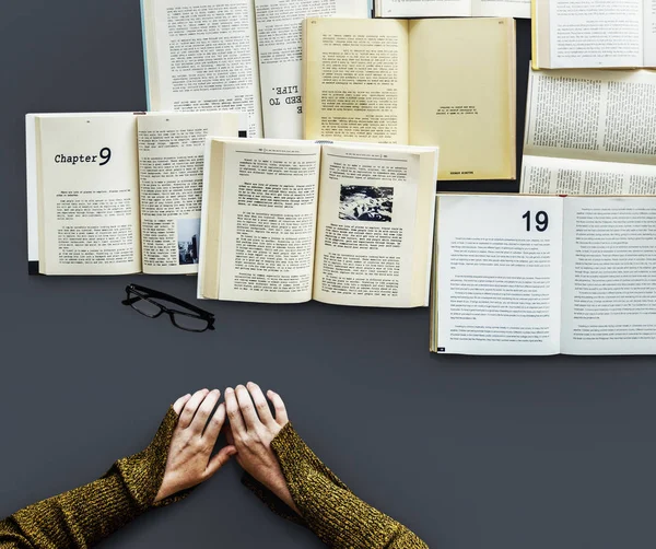 Руки за столом со многими книгами — стоковое фото