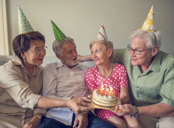 пожилые люди держат торт день рождения
