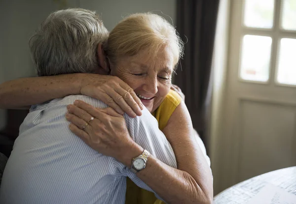 Пожилая пара обнимается в помещении — стоковое фото