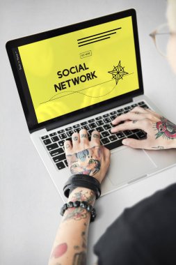 Dövmeli kişi dizüstü bilgisayarda yazarak.