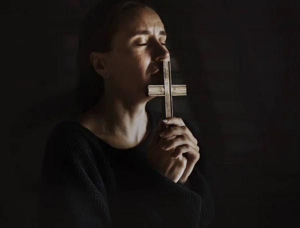 Lidende kvinne som holder kors og ber – stockfoto