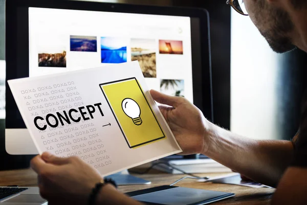 Man holding picture in front of monitor screen — Stock Photo, Image