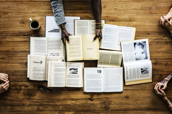 Hände am Tisch mit vielen Büchern — Stockfoto