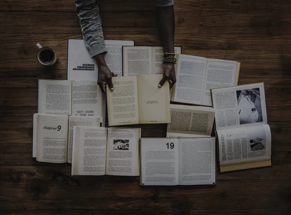 Hände am Tisch mit vielen Büchern — Stockfoto