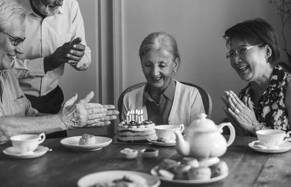 Starší žena s přáteli a narozeninový dort — Stock fotografie