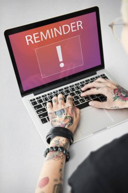 Dövmeli kişi dizüstü bilgisayarda yazarak.