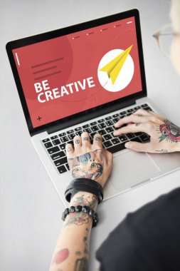 Dövmeli kişi dizüstü bilgisayarda yazarak.