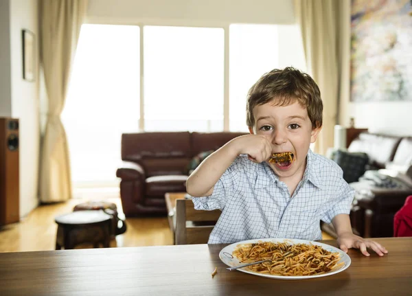 Niño comiendo espaguetis en casa — Foto de Stock