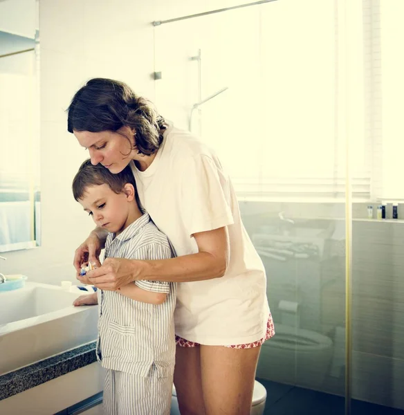 Mamá enseñando hijo a usar cepillo de dientes — Foto de Stock