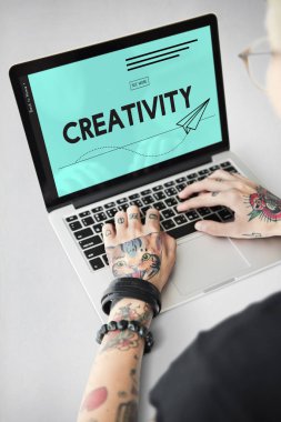 Dövmeli kişi dizüstü bilgisayarda yazarak.