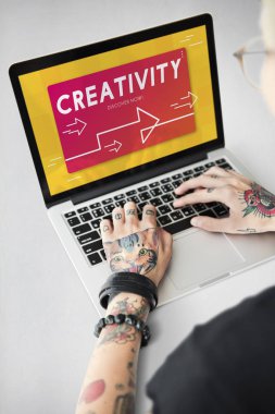 Dövmeli kişi dizüstü bilgisayarda yazarak.