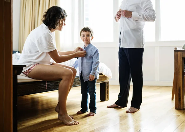 Padre y madre ayudando a su hijo a vestirse — Foto de Stock