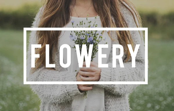 Жінка стоїть на полі і тримає квіти — стокове фото