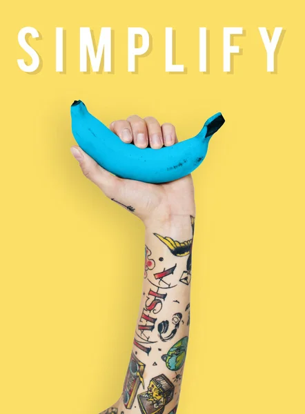 Tattooed person holding banana. — Stock Photo, Image