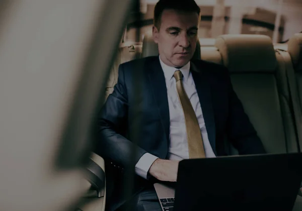 Affärsman med laptop i bilen — Stockfoto