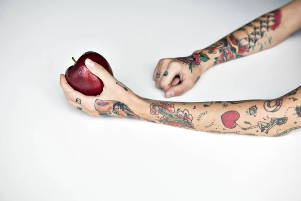 Getatoeëerde persoon bedrijf apple. — Stockfoto