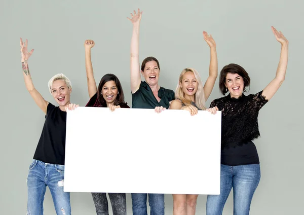 Mulheres sorridentes segurando banner vazio — Fotografia de Stock