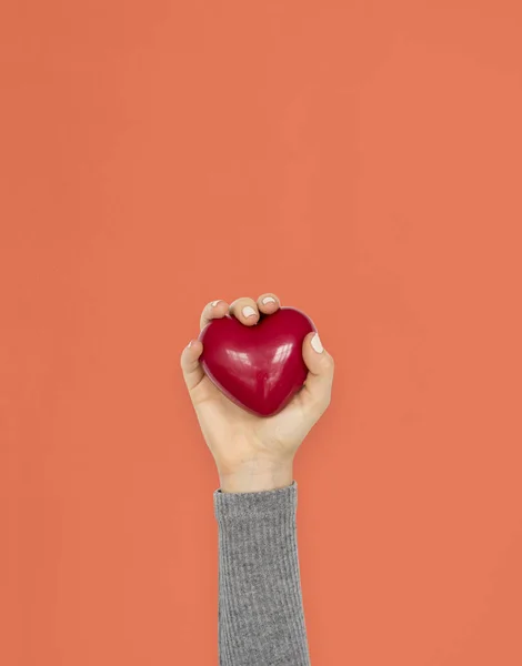 Mão segurando vermelho coração brinquedo — Fotografia de Stock