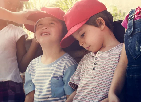 Crianças em bonés vermelhos se divertindo — Fotografia de Stock